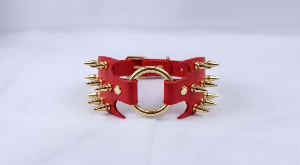 A red leather choker necklace with gold spikes protruding from it.