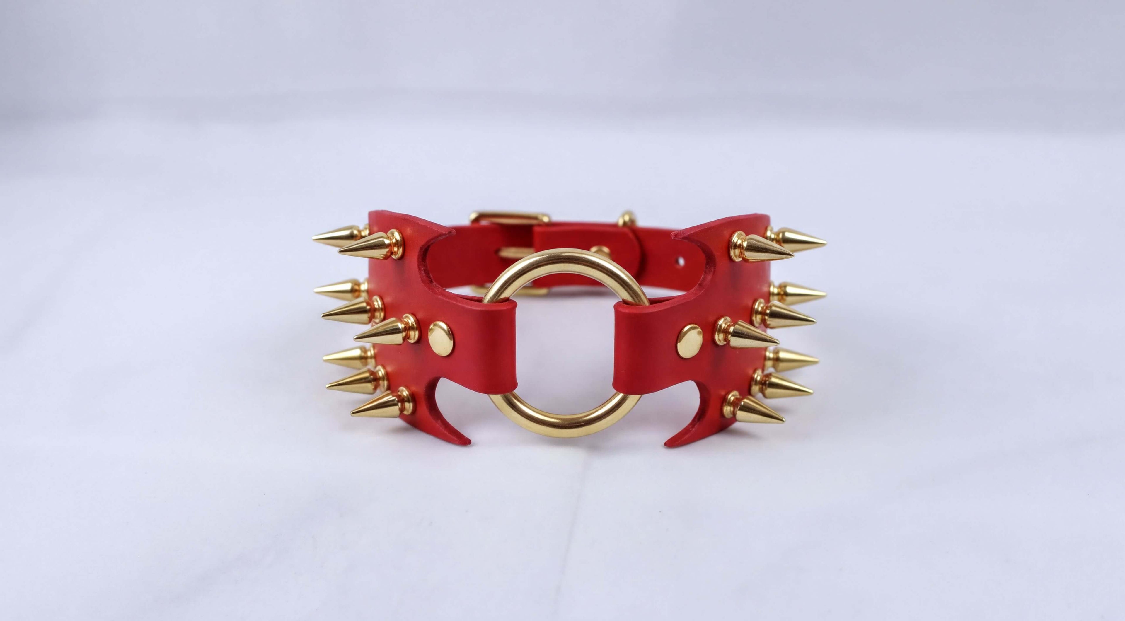 A red leather choker necklace with gold spikes protruding from it.