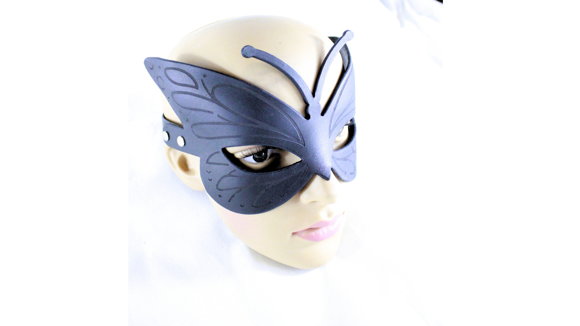 A mannequin head wearing a black butterfly-shaped mask.