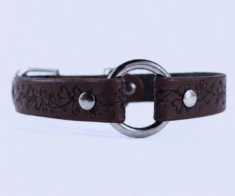 A brown leather collar with a metal ring and floral designs.