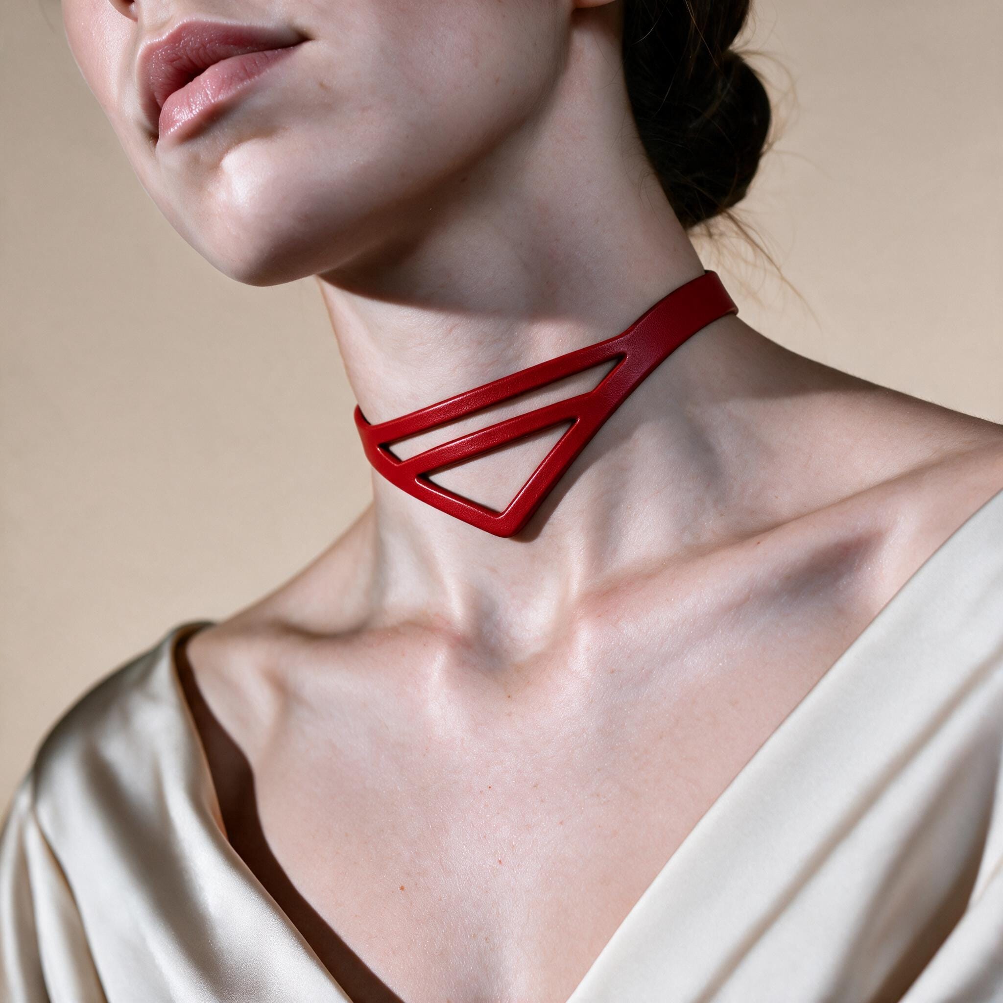 A close-up of a woman's neck and chest area, with a red choker necklace prominently displayed.