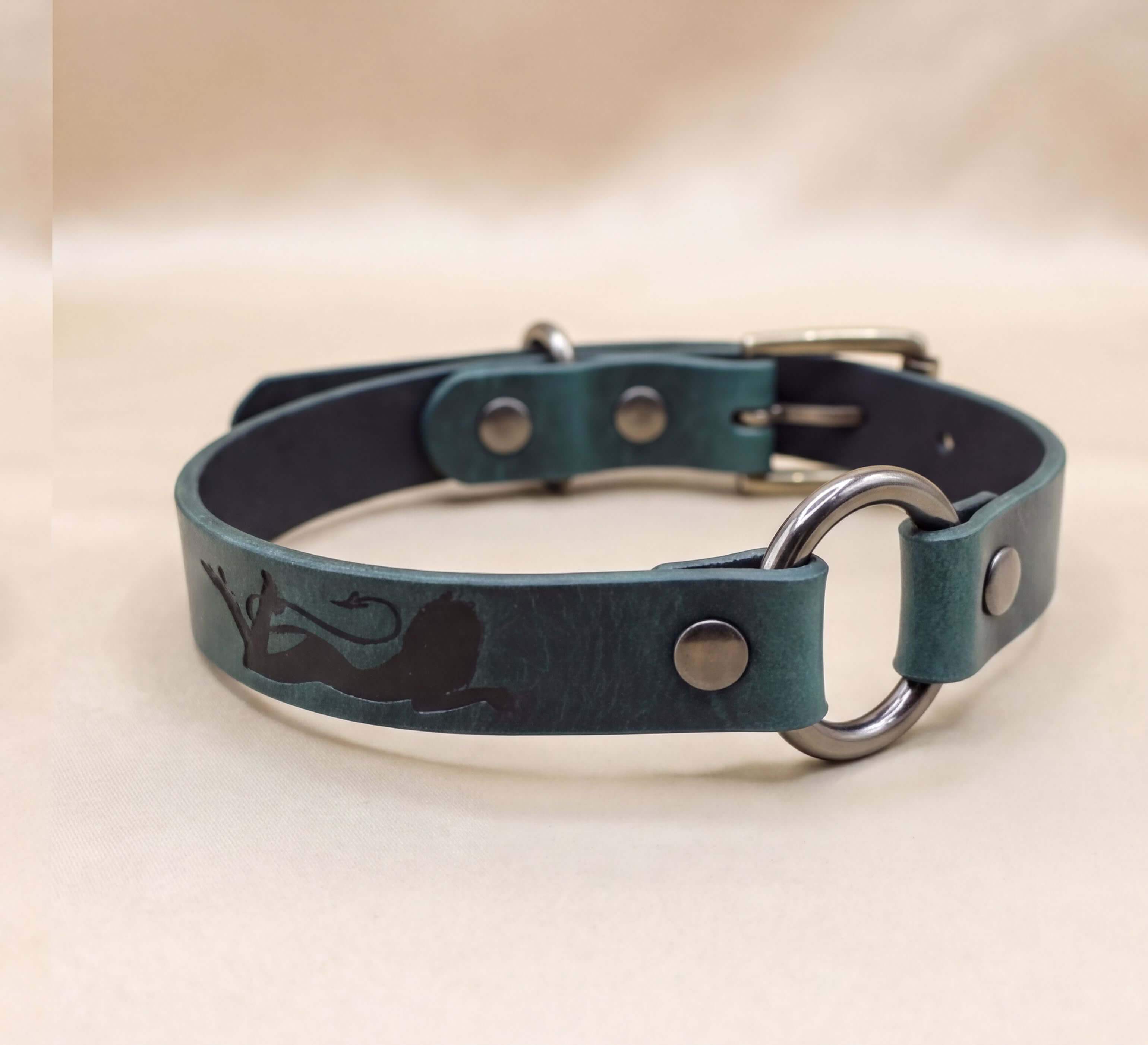 A green leather dog collar with a metal ring and buckle.