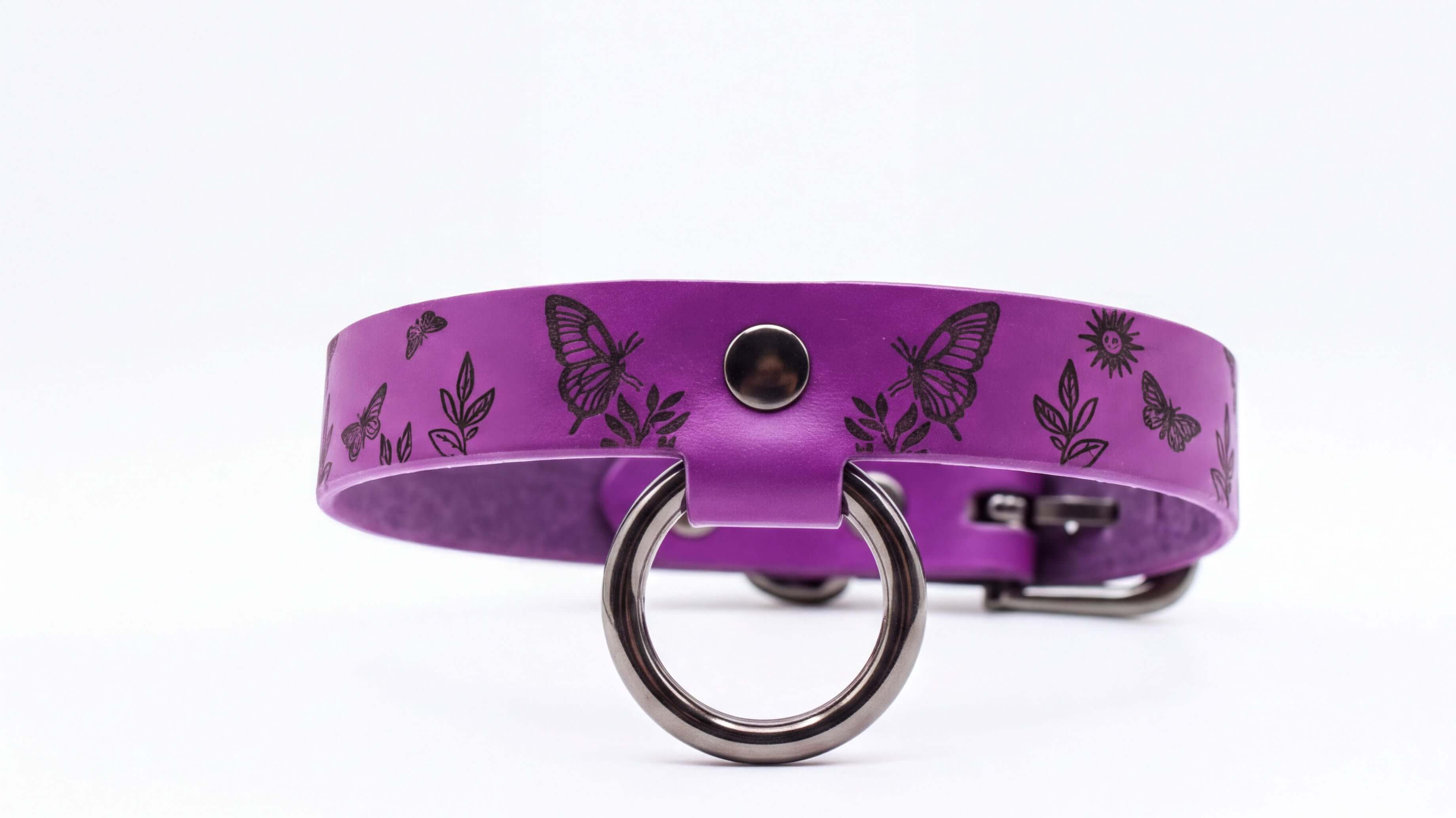 A purple leather collar with a metal ring and butterfly designs.