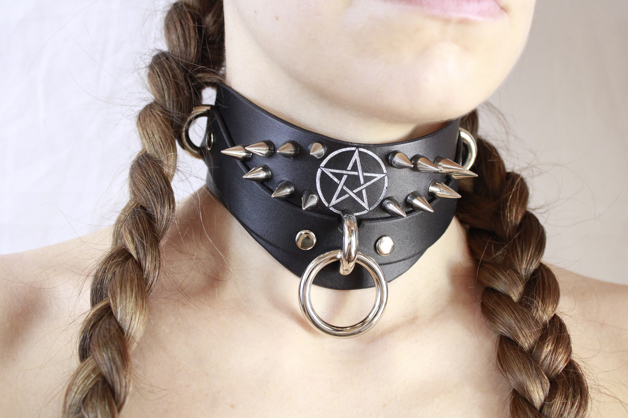 Close-up of a woman wearing a Pentagram BDSM Collar with spikes and a central ring.