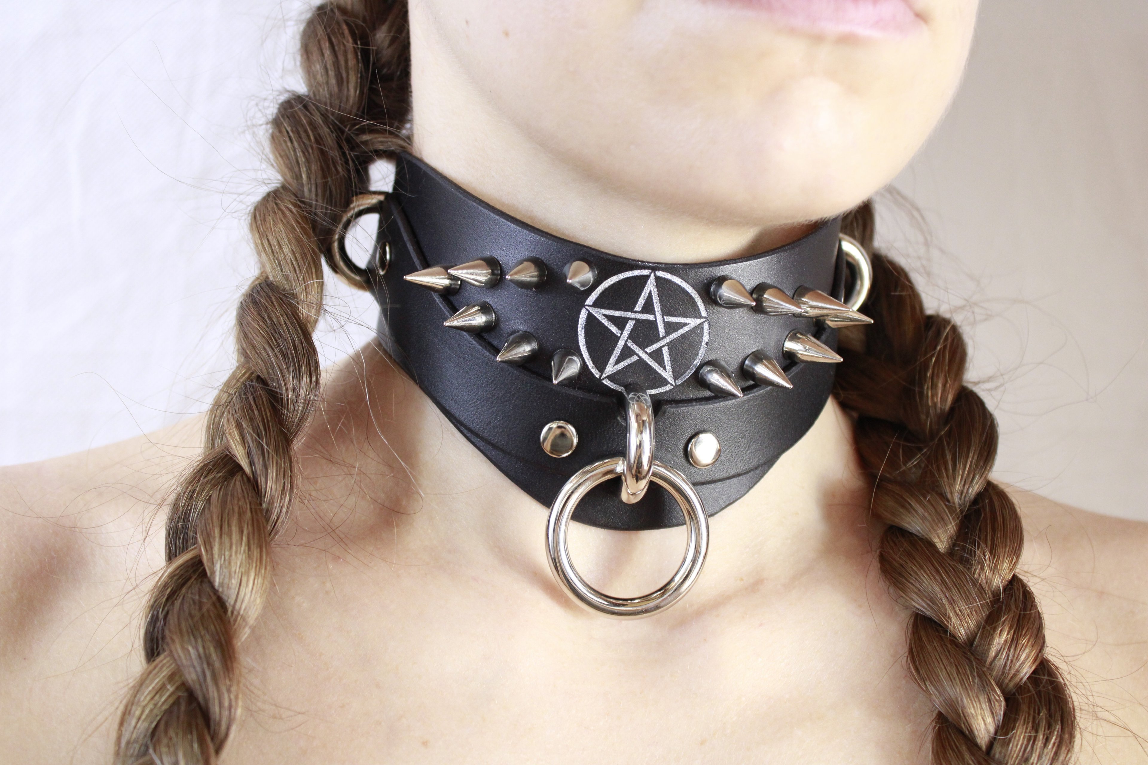 Close-up of a woman wearing a Pentagram BDSM Collar with spikes and a central ring.