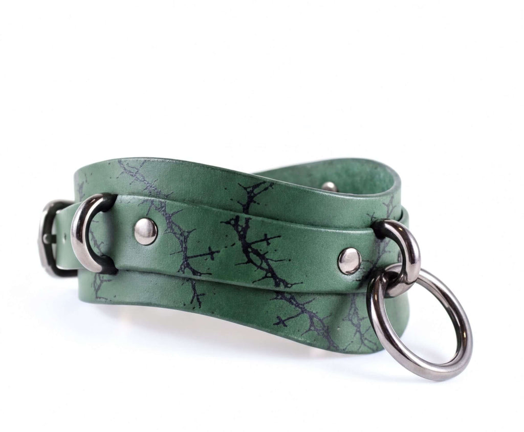 A green leather choker necklace with metal rings and a metal buckle.