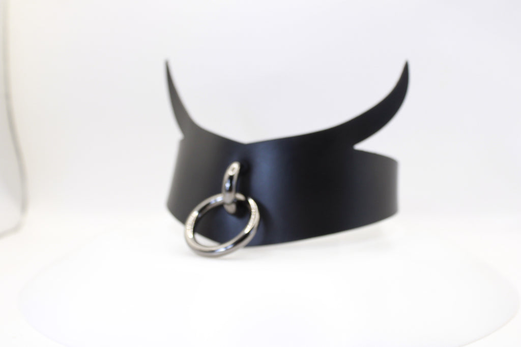 A black leather choker necklace with a silver ring and two curved horns.