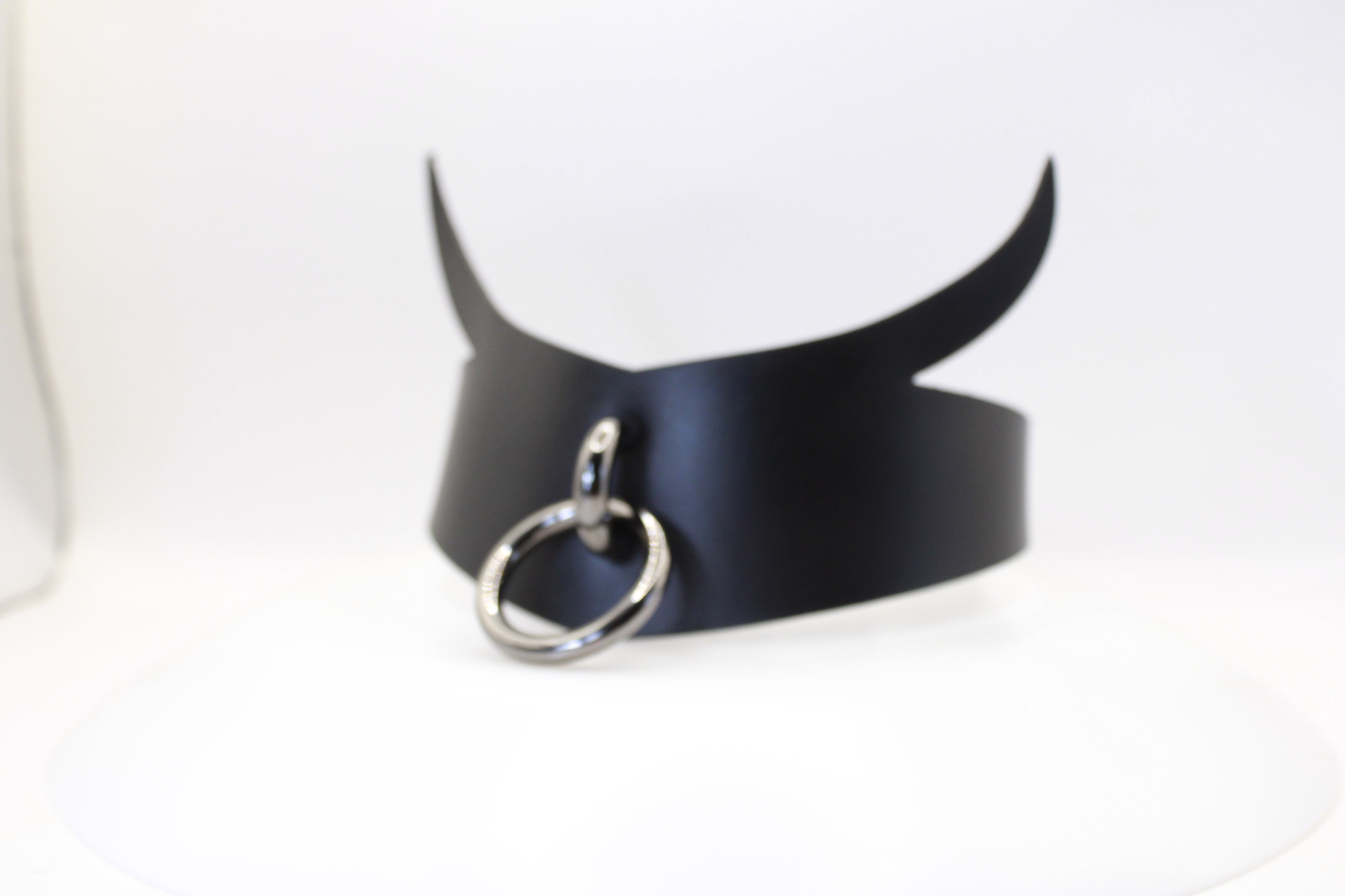 A black leather choker necklace with a silver ring and two curved horns.
