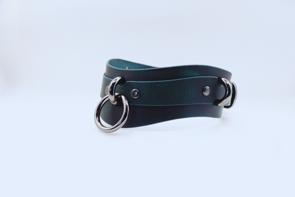 A dark green leather choker necklace with metal rings and buckles.