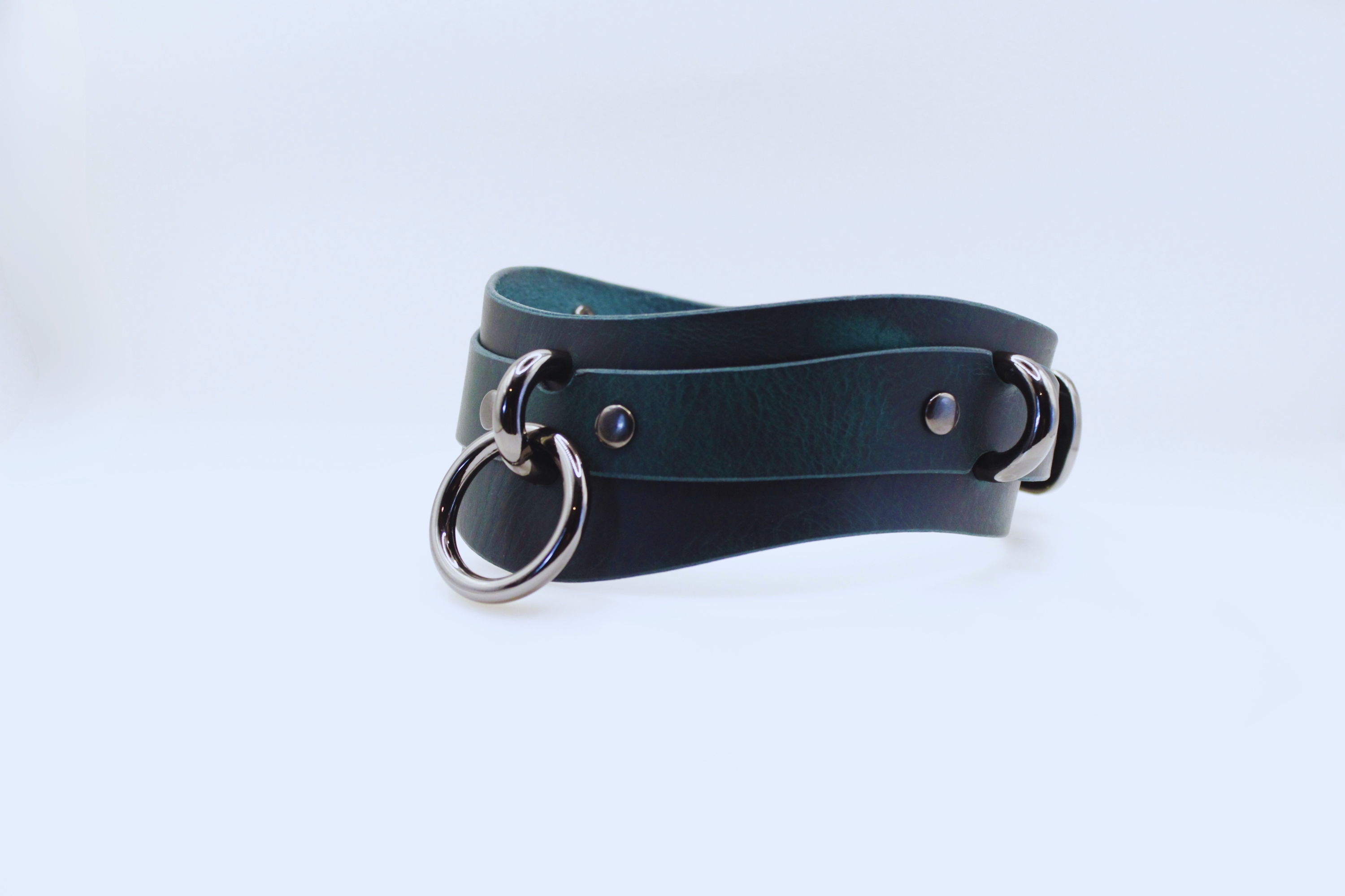 A dark green leather choker necklace with metal rings and buckles.