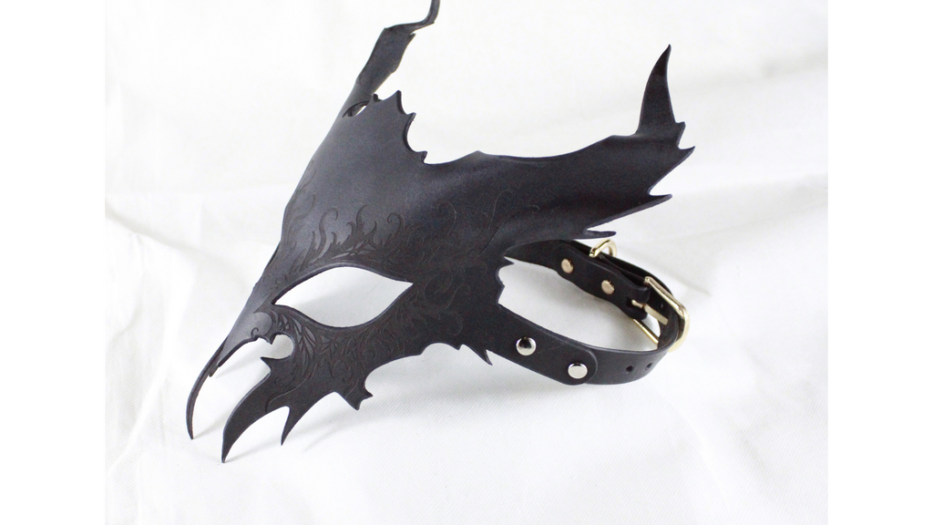 A black leather mask with a pointed, winged design and a black strap.