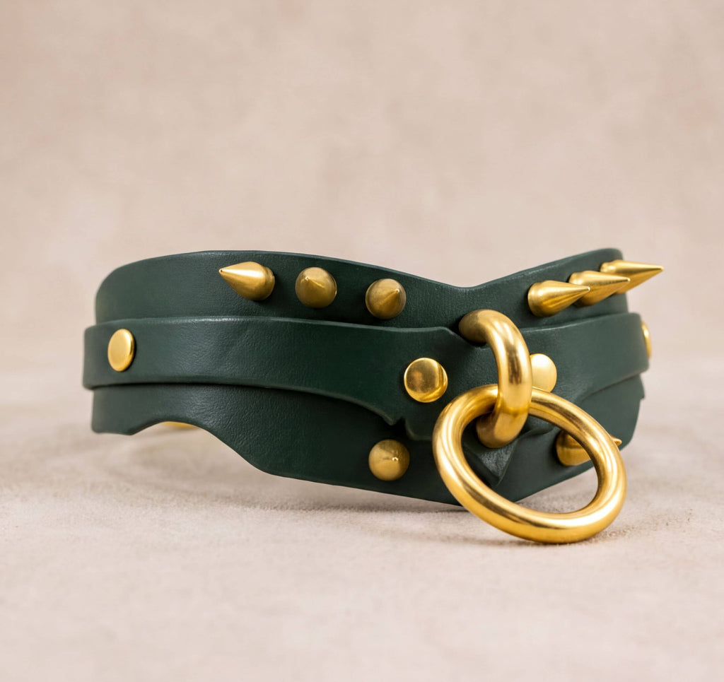 A green leather choker necklace with gold studs and a gold ring on the front.