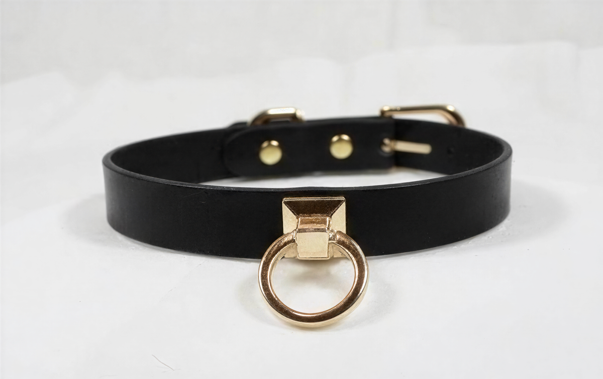 A black leather choker collar with a gold-colored metal ring and buckle.
