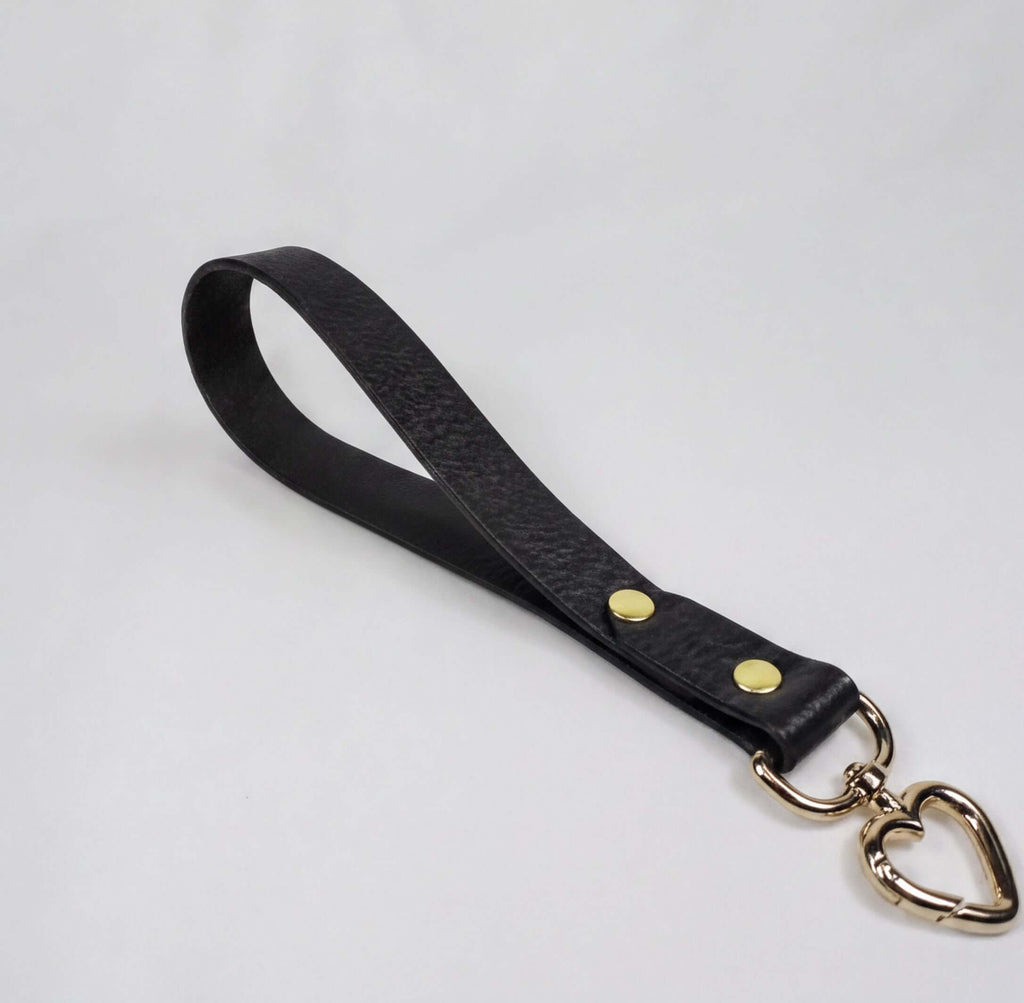 A black leather strap with a heart-shaped metal clasp attached to it.