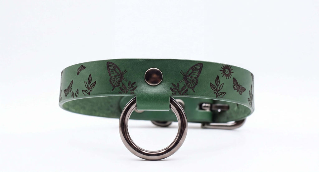 A green leather collar with a metal ring and butterflies printed on it.