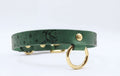 A green leather collar with a moon and star design, featuring a gold-colored metal ring on the front.