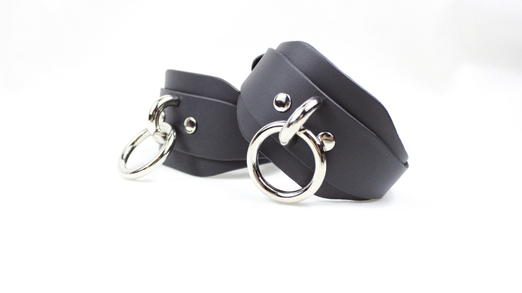A pair of black leather choker necklaces with silver metal rings and buckles.