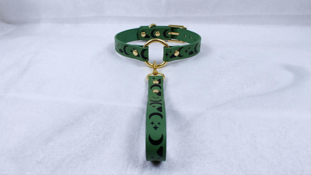 A green collar with a gold buckle and a matching green leash attached to it, resting on a white surface.