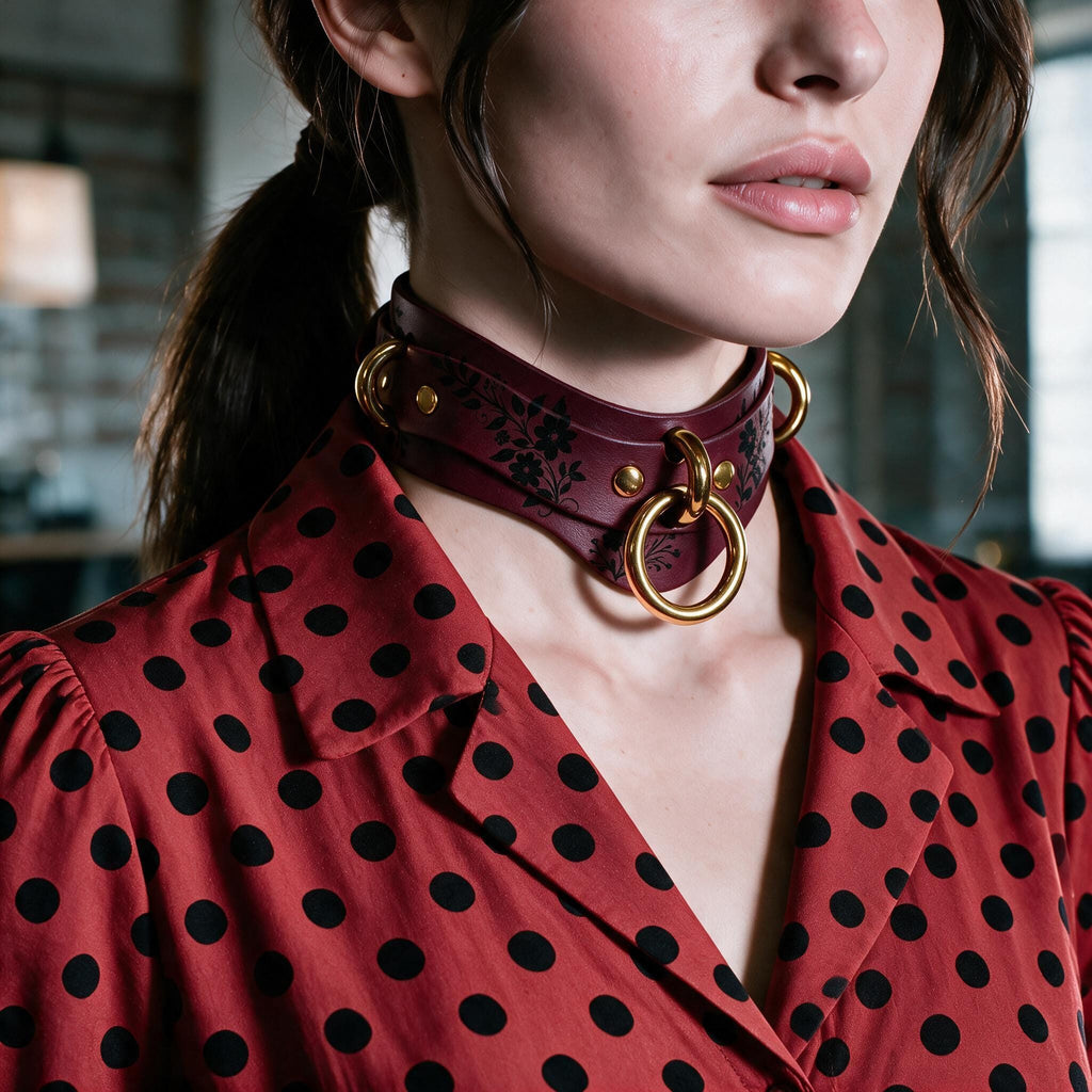 A close-up of a woman wearing a red polka dot blouse with a choker necklace featuring gold rings.
