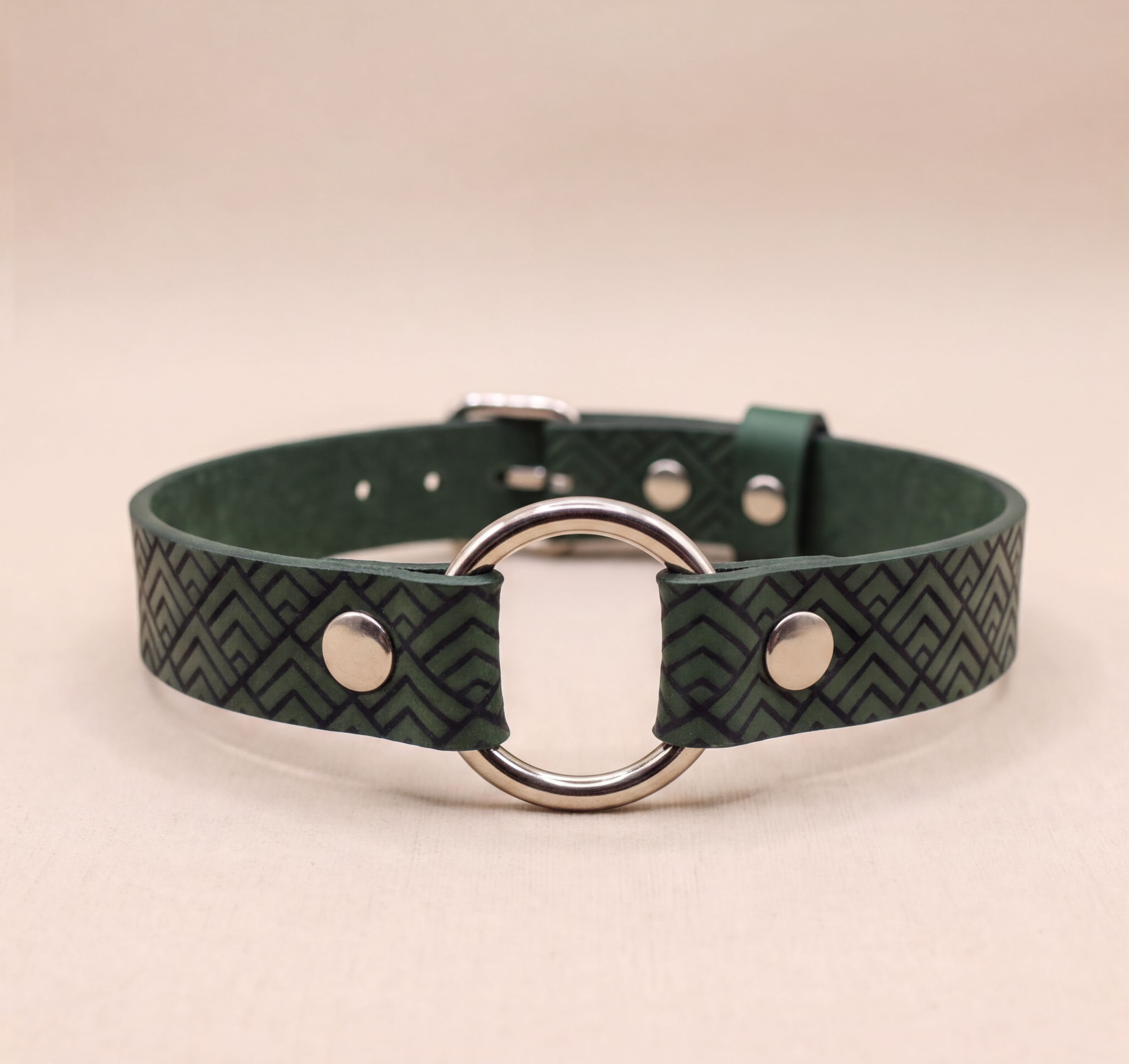 A green leather choker collar with a metal ring and two metal buttons.
