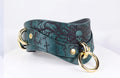 A green leather choker necklace with a skull design and gold-colored metal rings.