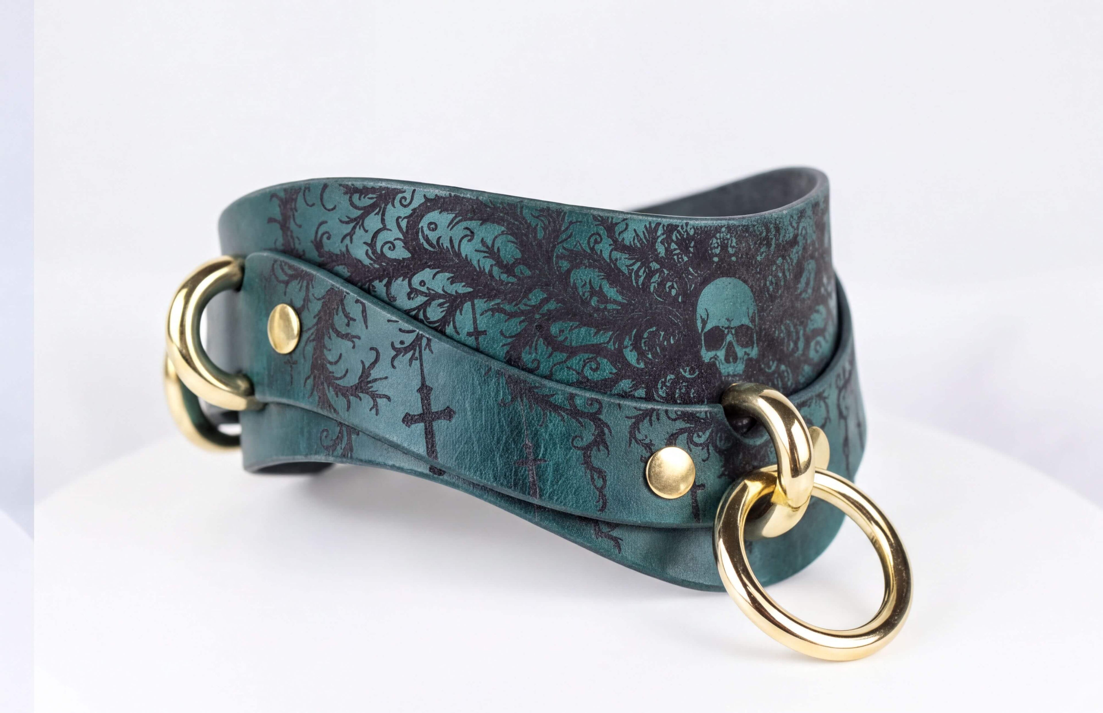 A green leather choker necklace with a skull design and gold-colored metal rings.