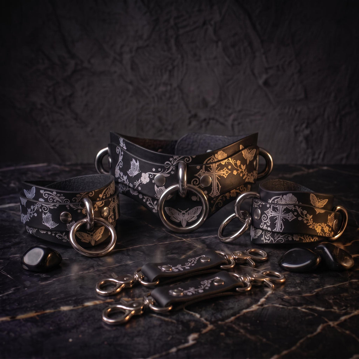 a collection of leather straps and buckles, each adorned with intricate floral designs, arranged on a dark surface.