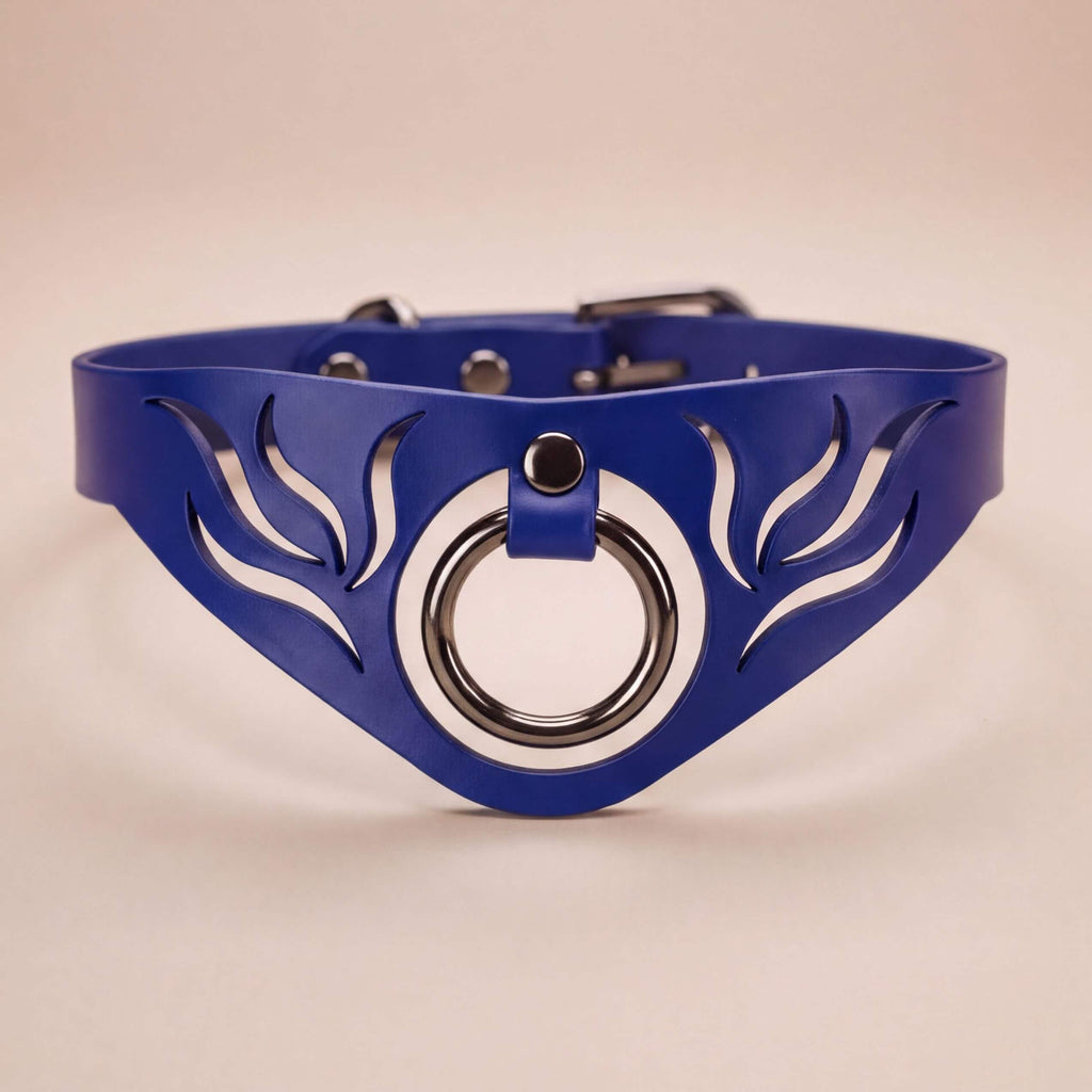 A blue leather choker necklace with a circular metal ring and a decorative leaf-like design on the front.