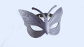 A black butterfly-shaped mask with intricate designs on its wings and a black strap.