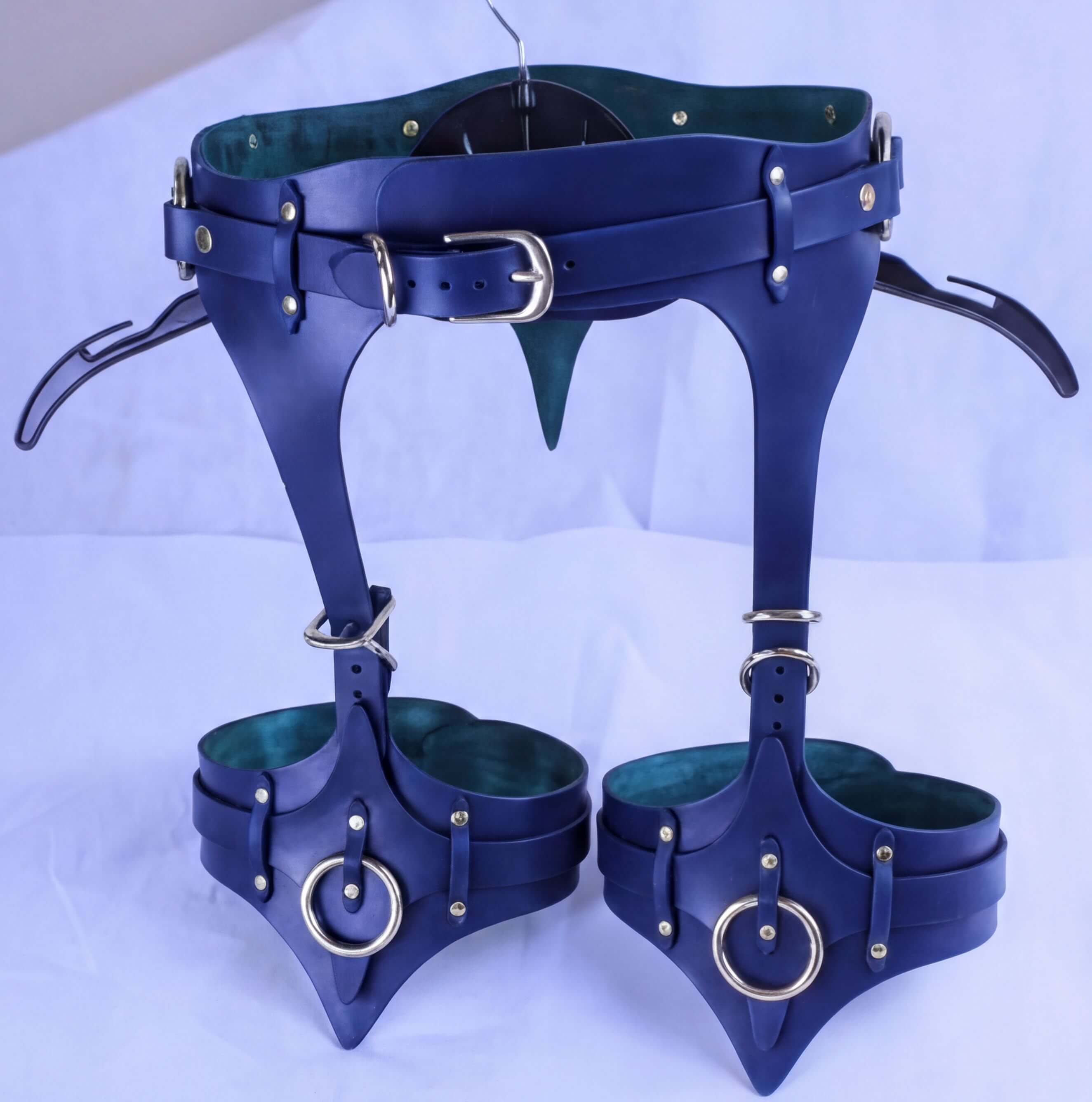 A pair of blue leather corsets with metal hardware, including buckles and rings, displayed on a white background.