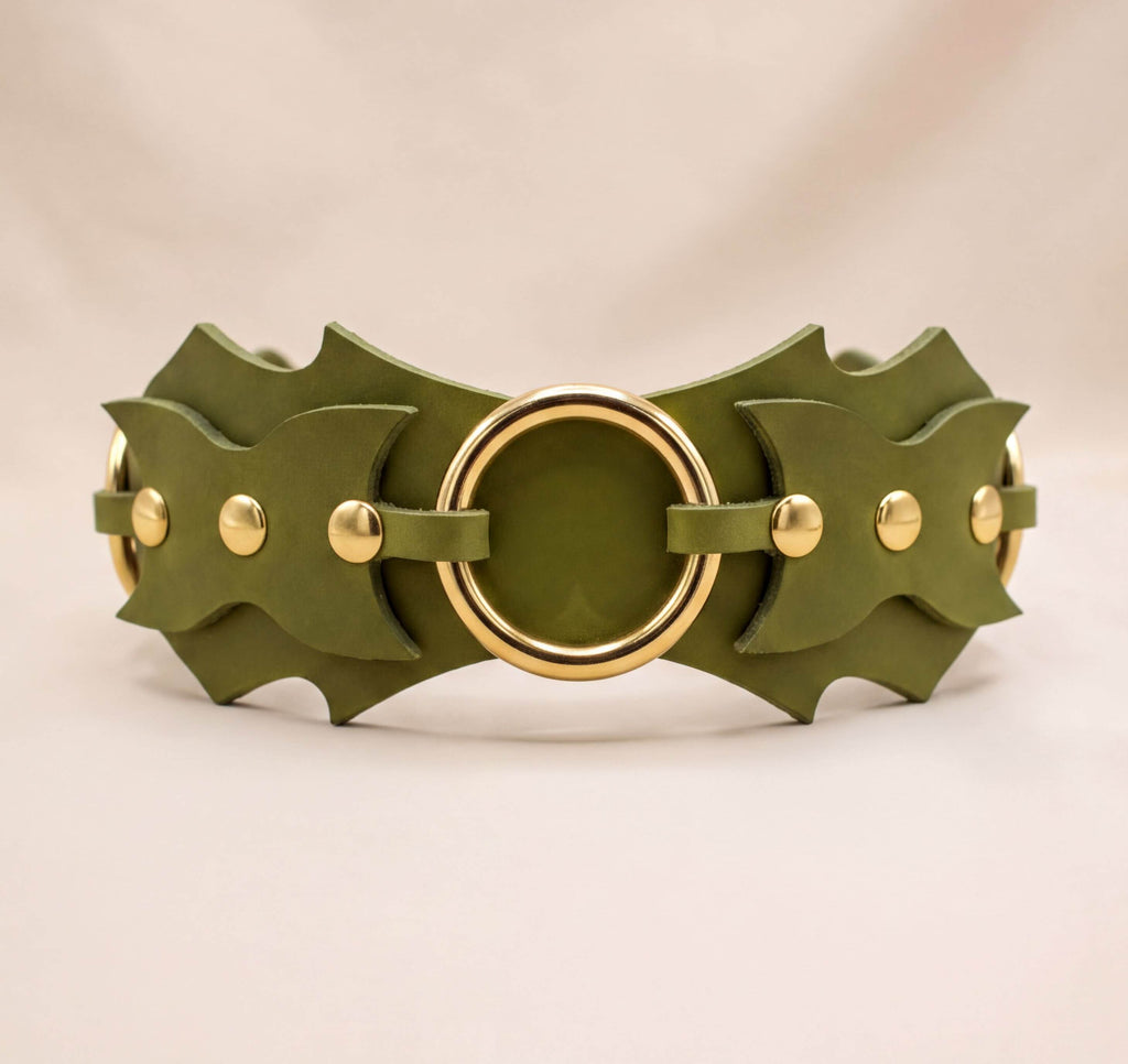 A green leather belt with gold-colored metal studs and a circular buckle.