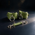 a pair of green leather straps with metal rings and a green leather strap with metal rings, all placed on a dark surface.