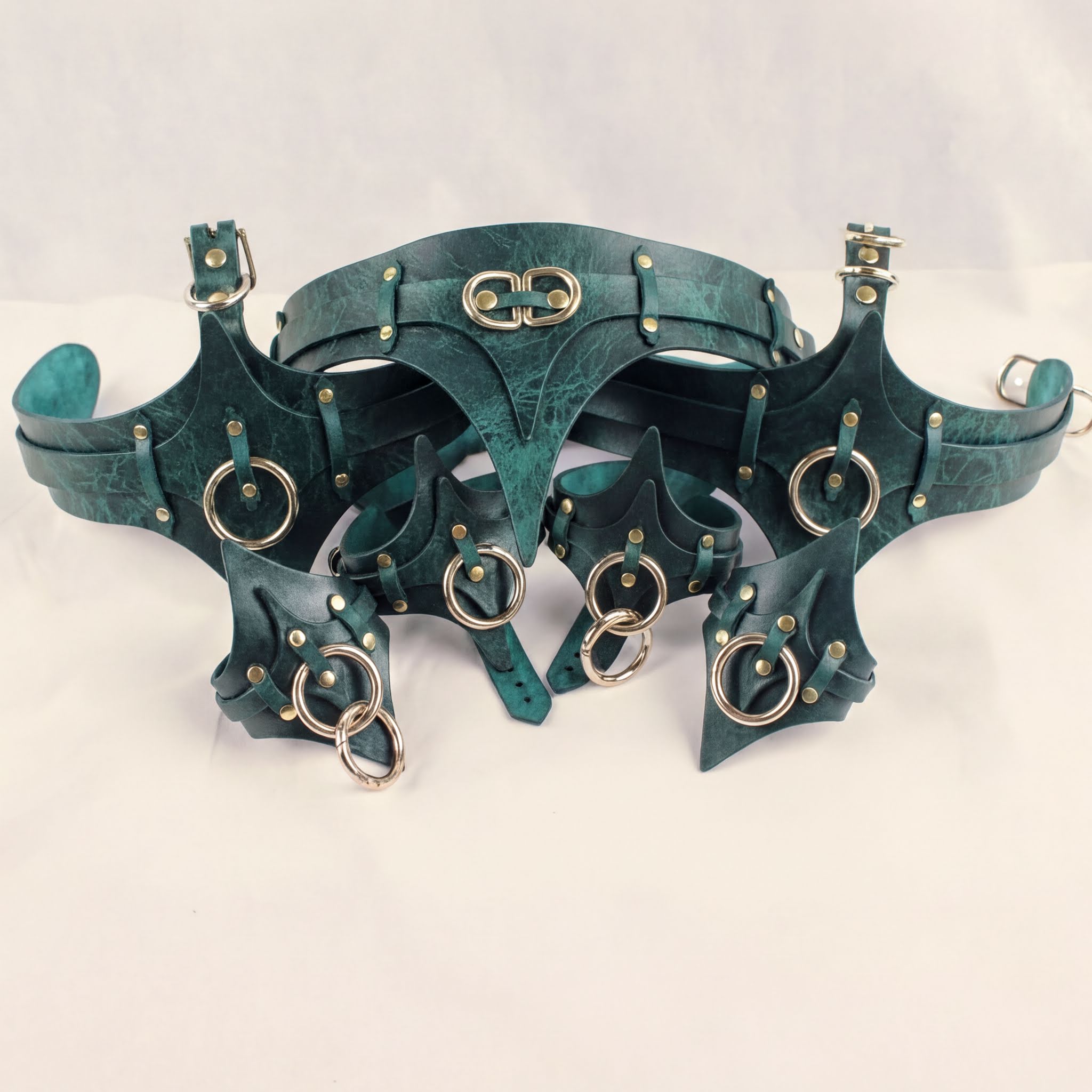A collection of green leather straps with metal rings and buckles, arranged in a decorative manner.