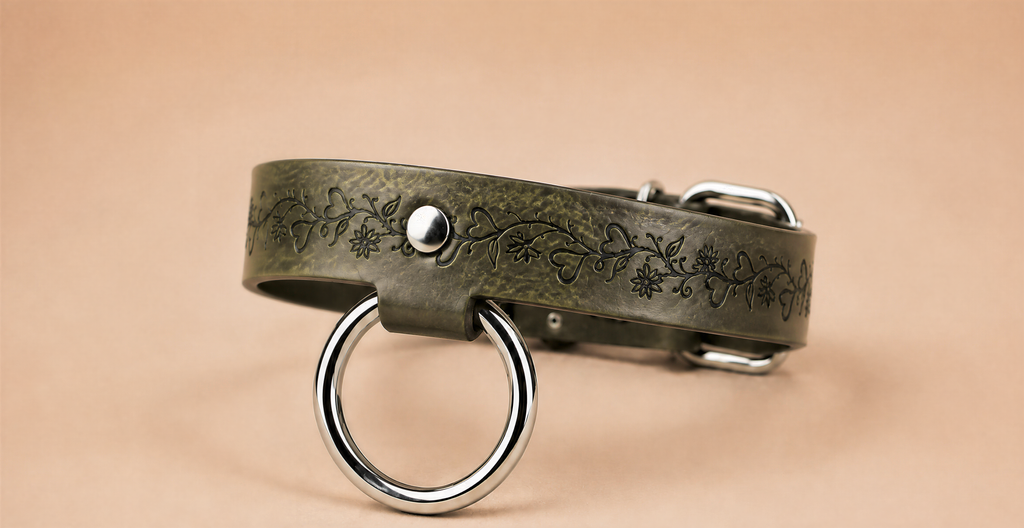 A green leather collar with a metal ring and a floral design on the band.
