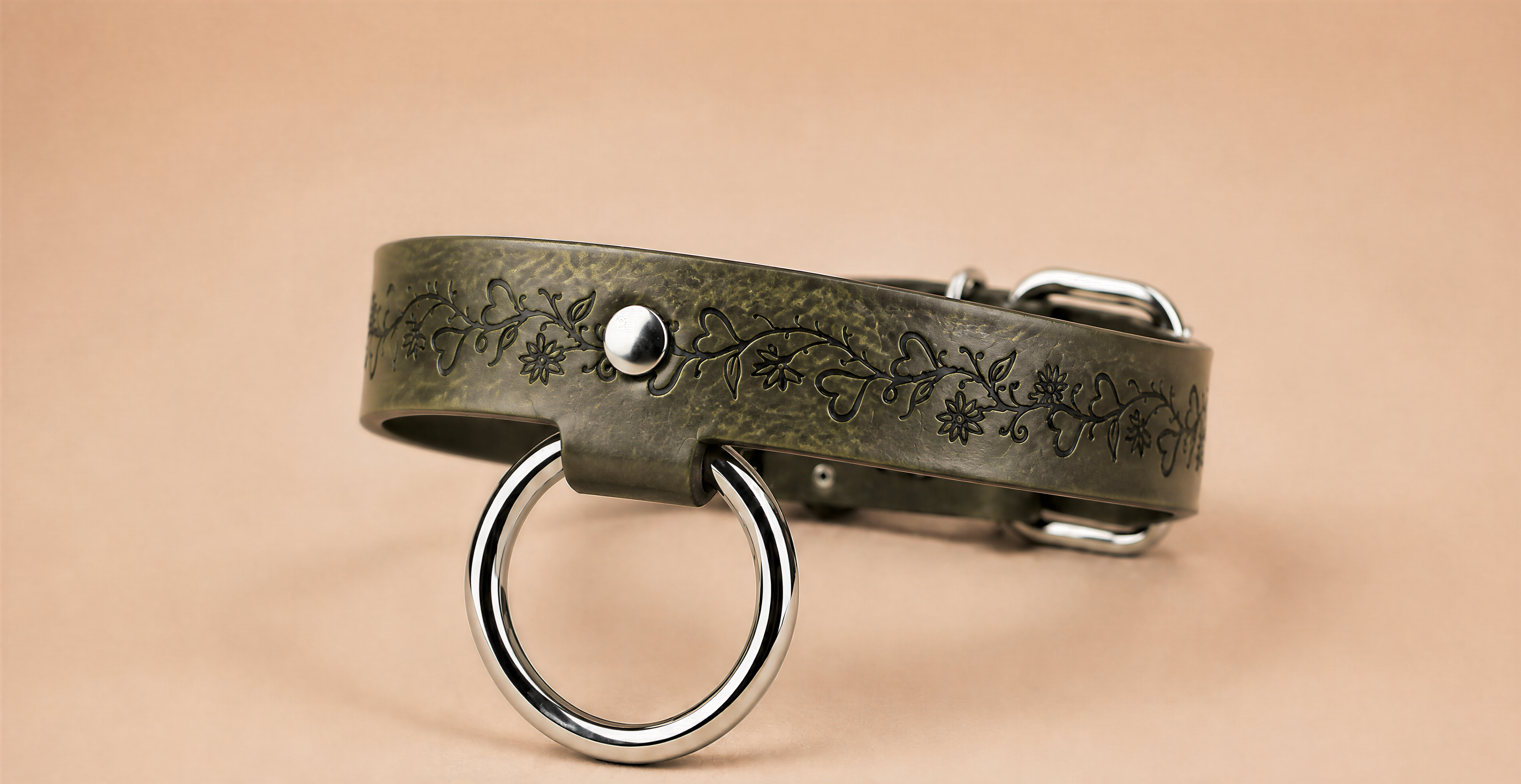 A green leather collar with a metal ring and a floral design on the band.