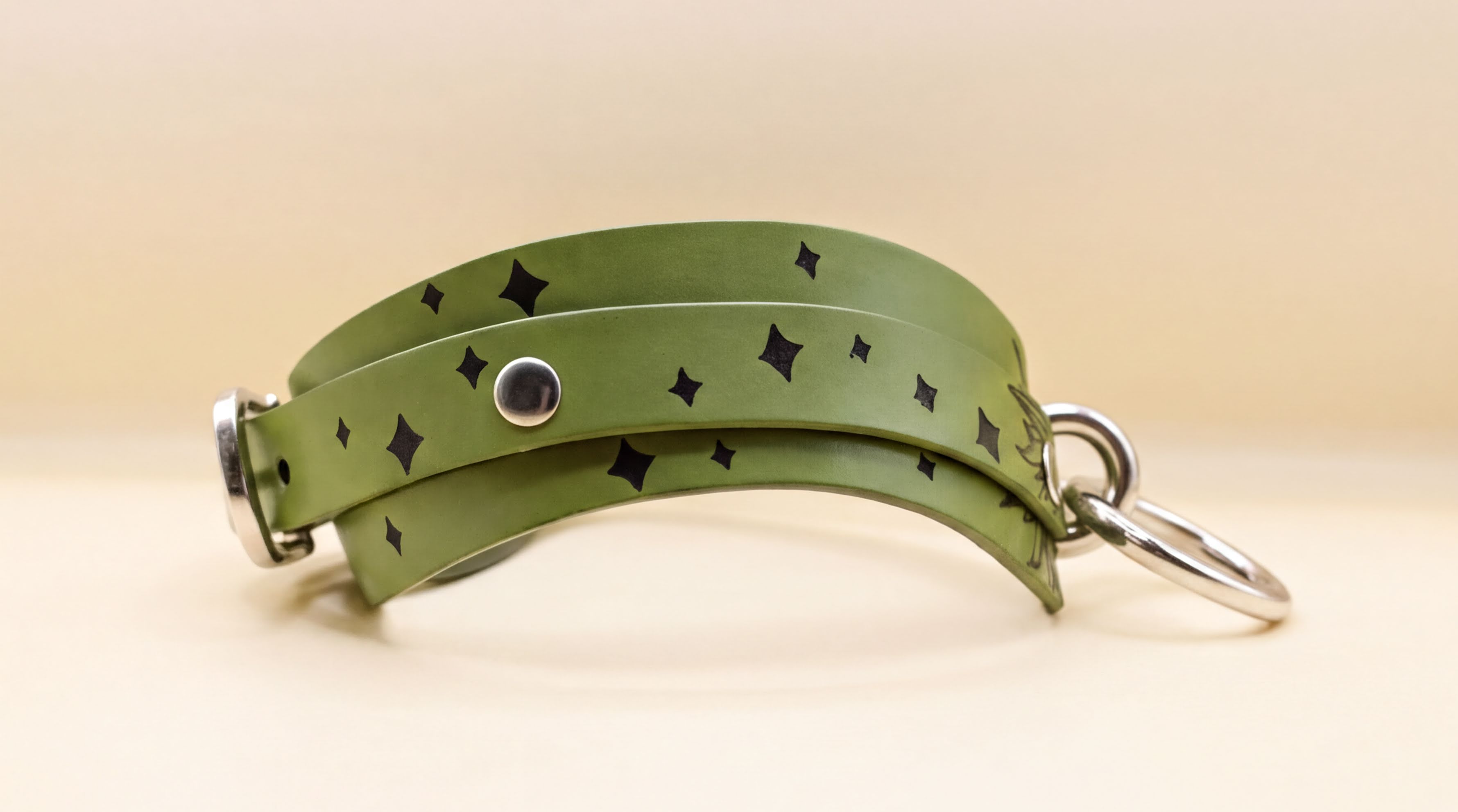 A green leather choker necklace with black diamond-shaped embellishments on the surface.
