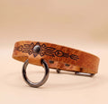 A brown leather dog collar with a metal ring and a decorative pattern on the leather.