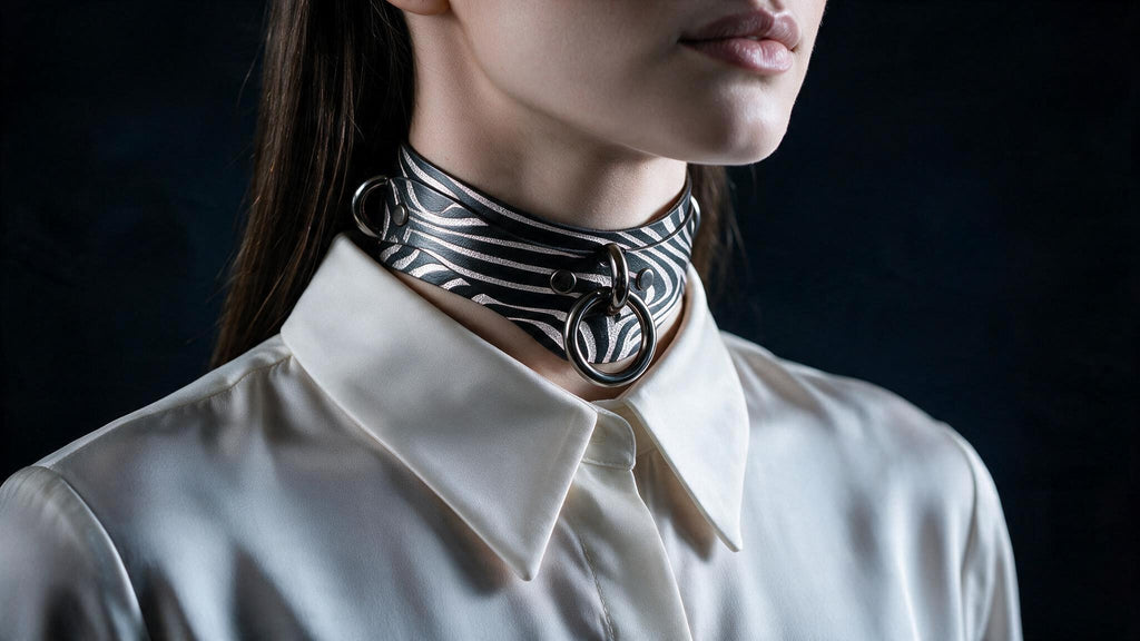 A close-up of a woman wearing a white collared shirt with a black and white zebra print choker necklace.