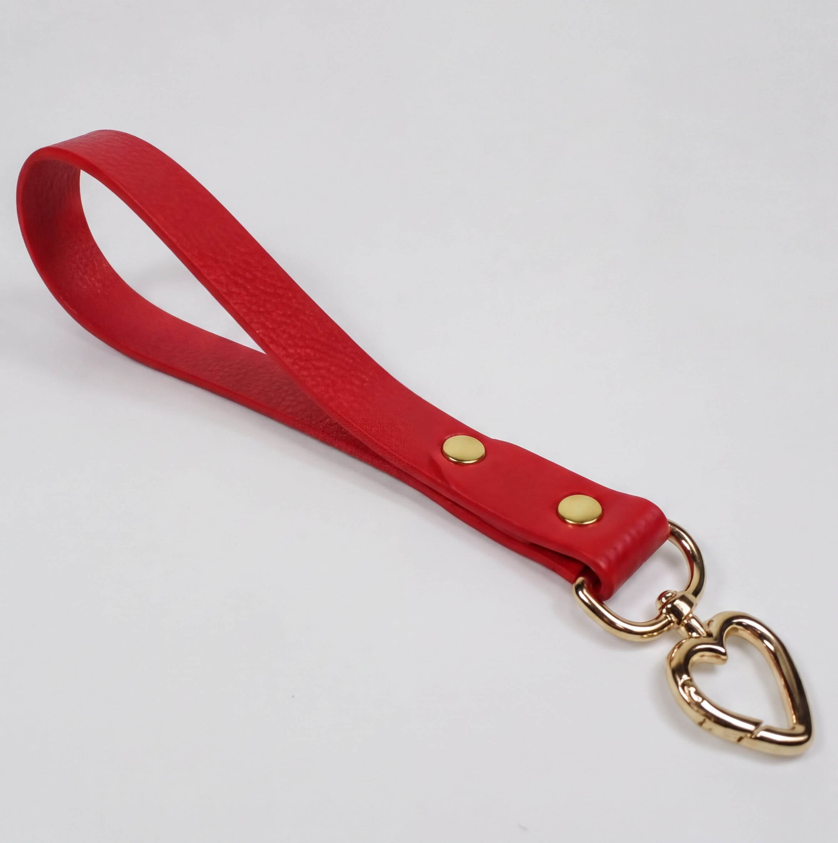 A red leather strap with a heart-shaped metal clasp attached to it.