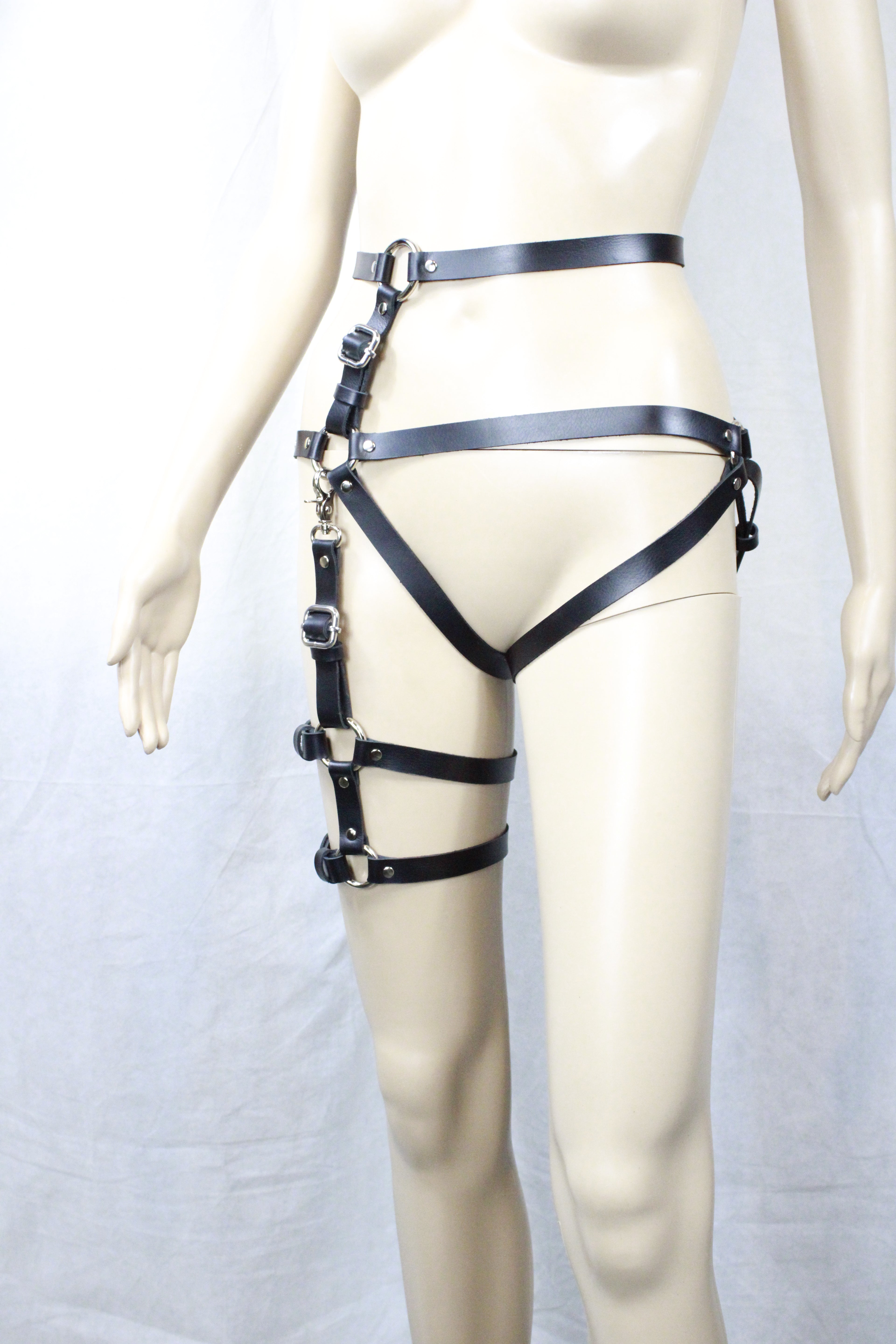 A mannequin wearing a black leather strap with multiple buckles and straps, creating a unique and edgy fashion statement.