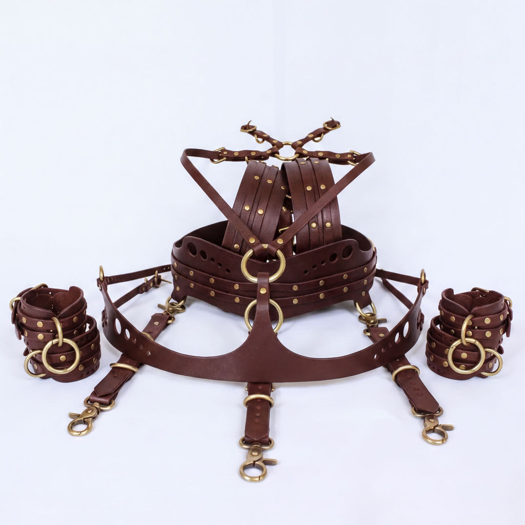 A leather harness with multiple straps and buckles, including a chest harness and wrist cuffs, all of which are brown in color.