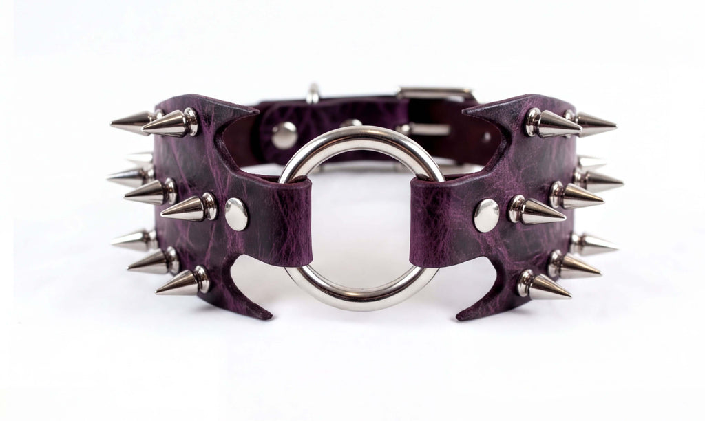 A purple leather choker necklace with a metal ring and spikes protruding from it.