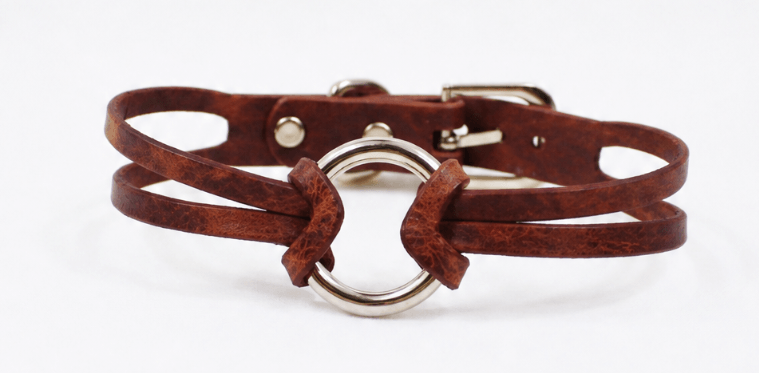 A brown leather choker necklace with a metal ring buckle.