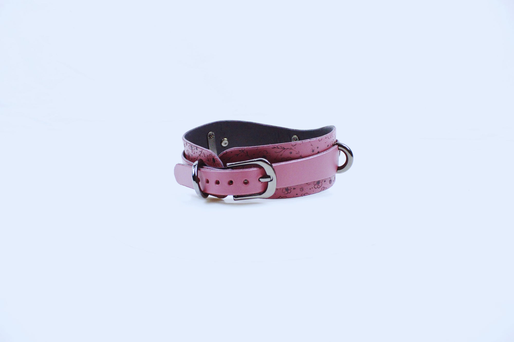 A pink leather collar with a metal buckle is shown against a white background.