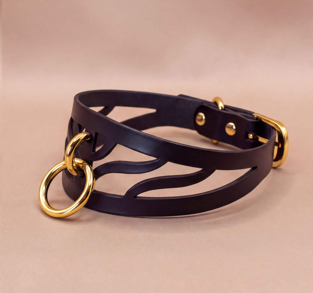 A black leather choker necklace with a gold-colored metal ring and buckle.