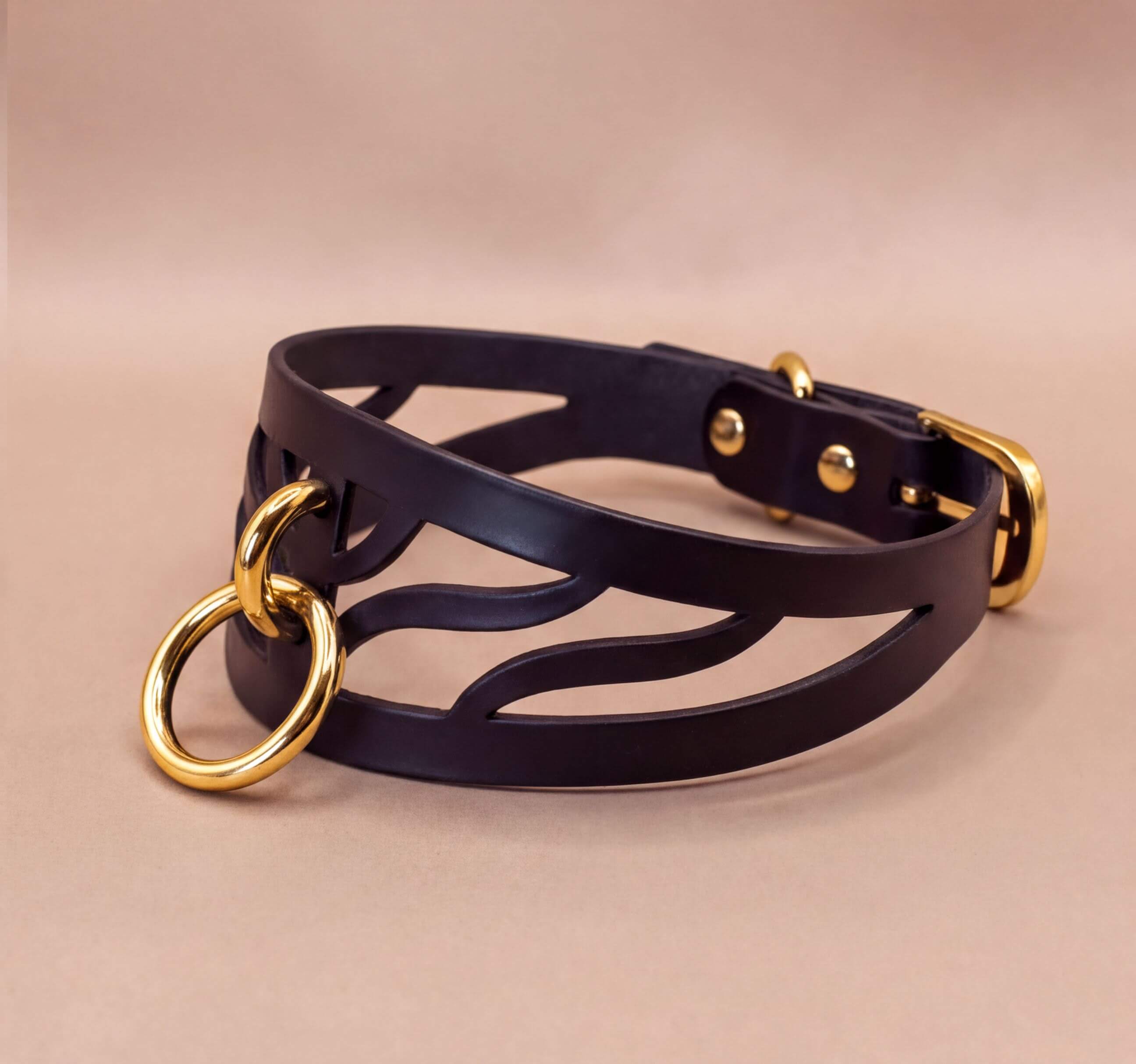A black leather choker necklace with a gold-colored metal ring and buckle.