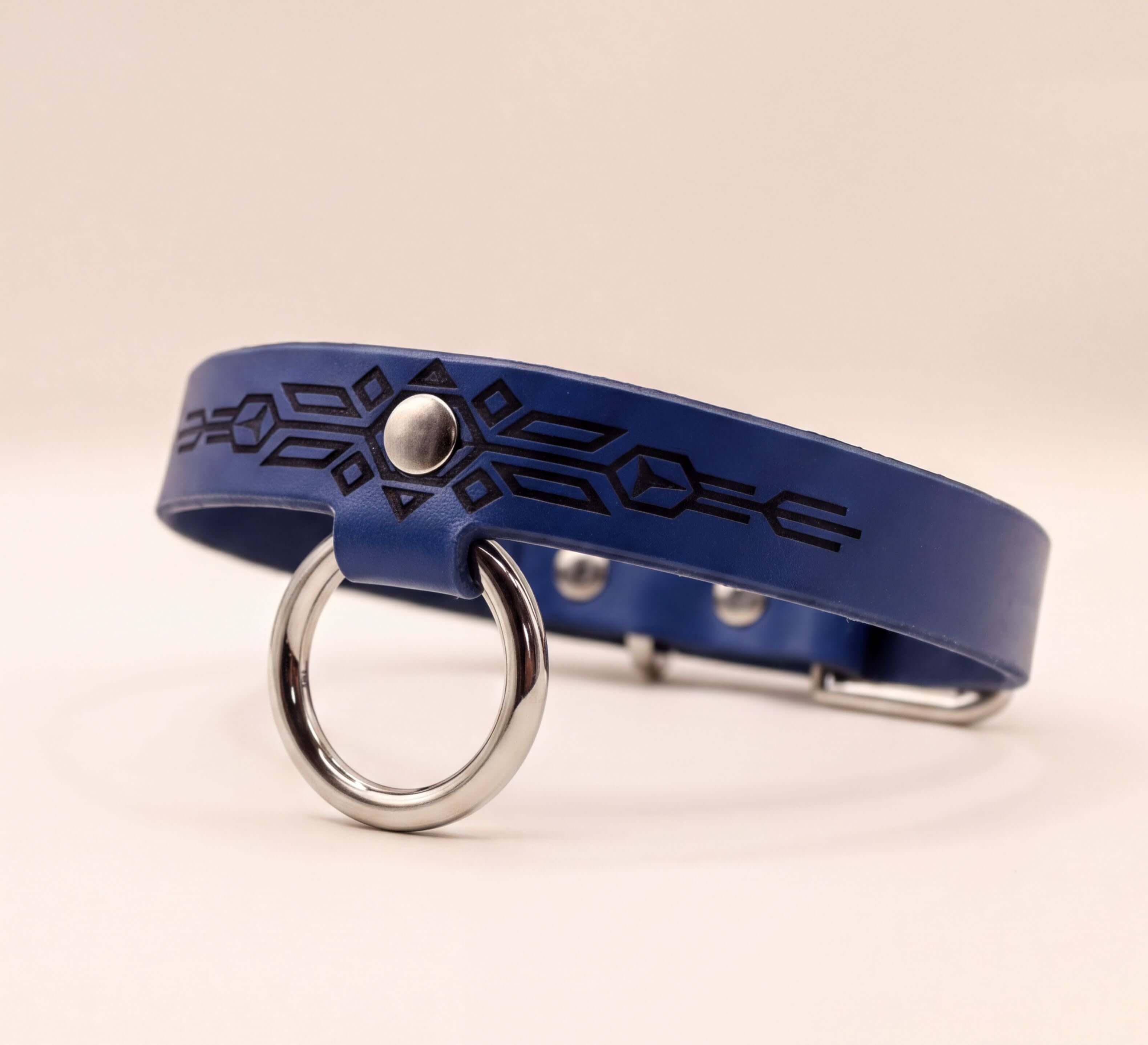 A blue leather collar with a silver ring and geometric design on it.