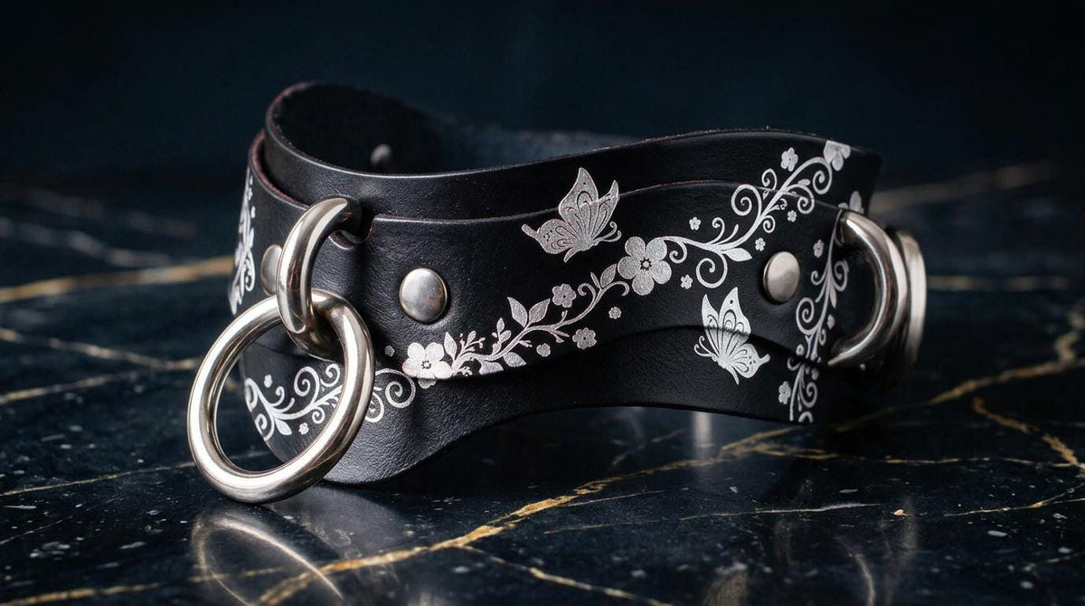 A black leather choker necklace with silver metal rings and a floral design on the clasp.