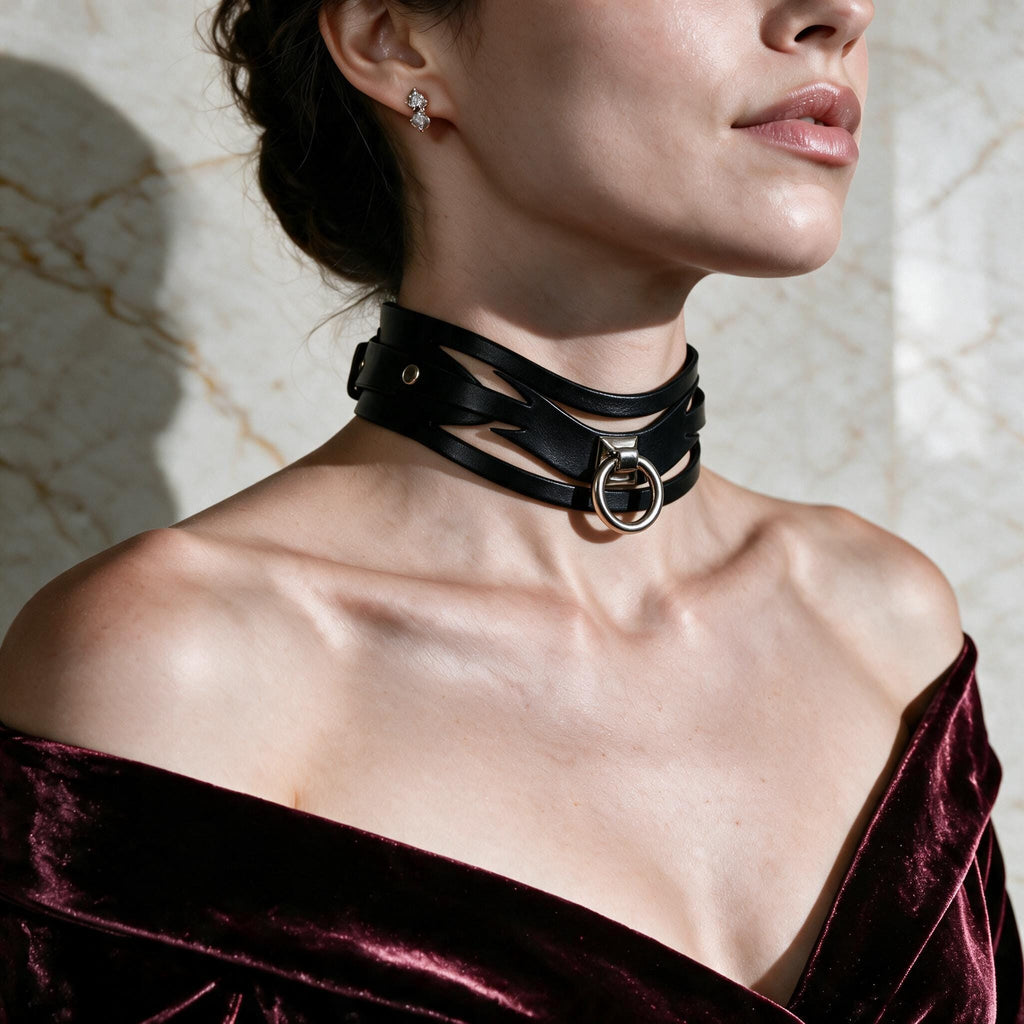 A woman wearing a black choker necklace with a large circular buckle, a burgundy velvet off-the-shoulder dress, and a gold earring.