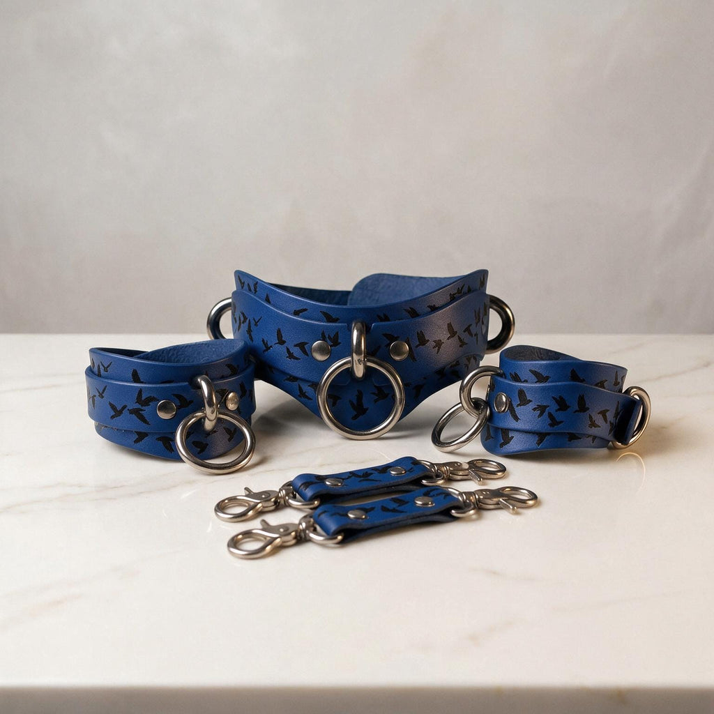 A set of blue leather straps with metal rings and buckles, arranged on a white marble surface.